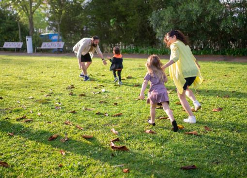 A joyful family playing together in a lush green park setting, enjoying a bright day.