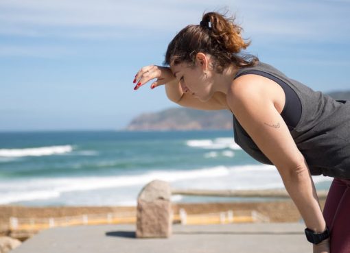 A woman rests after exercise, overlooking the ocean in Portugal's scenic seascape.